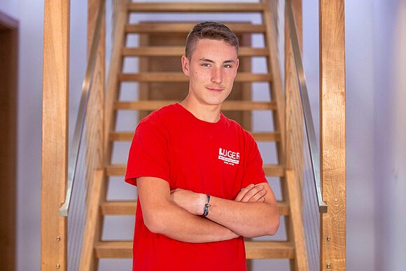 junger Mann in rotem T-shirt vor Treppe