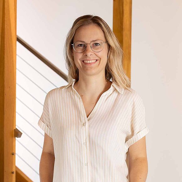 Blonde Frau mit heller Bluse und Brille