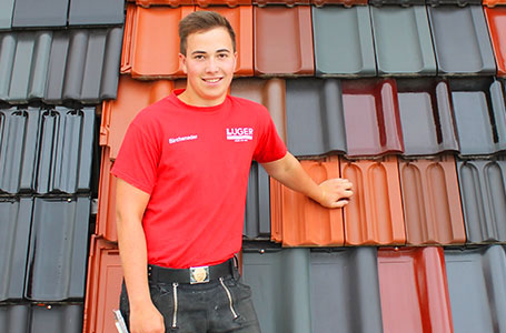 junger Mann in rotem T-shirt vor Dachziegeln